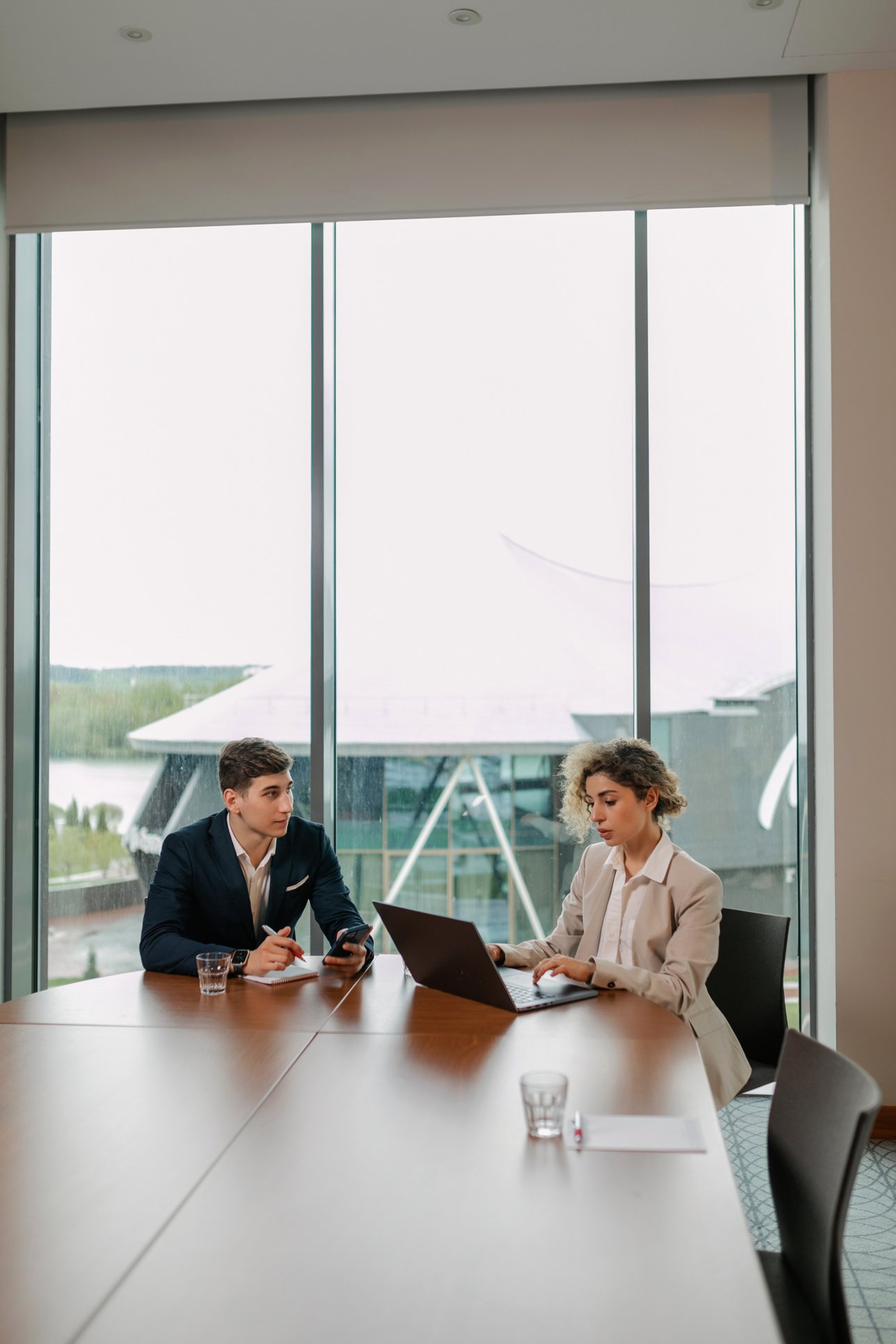 Two People Sitting at Table with Laptop Near the Window